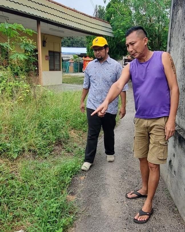 Aman Akil bersama seorang penduduk meninjau tepi laluan di Pekan Rembia.