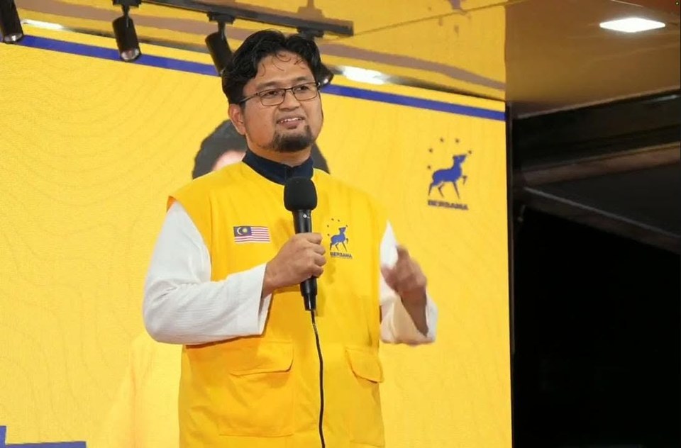 Penceramah memegang mikrofon di pentas Trak Kancil dengan latar kuning BERSAMA.