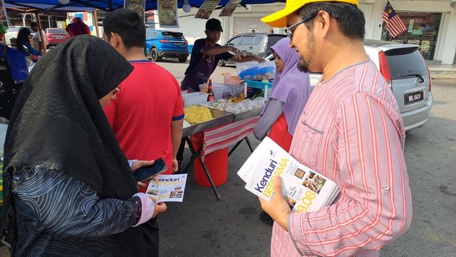 Aman Akil menyampaikan risalah Kenduri BERSAMA #3 kepada seorang pengunjung berhampiran gerai makanan.