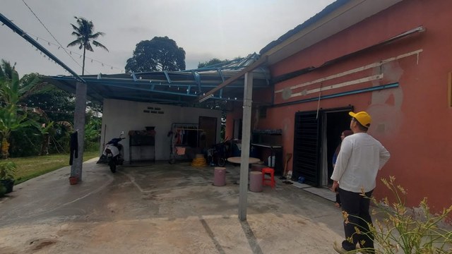 Aman Akil meninjau keadaan bumbung rumah yang rosak semasa ziarah.