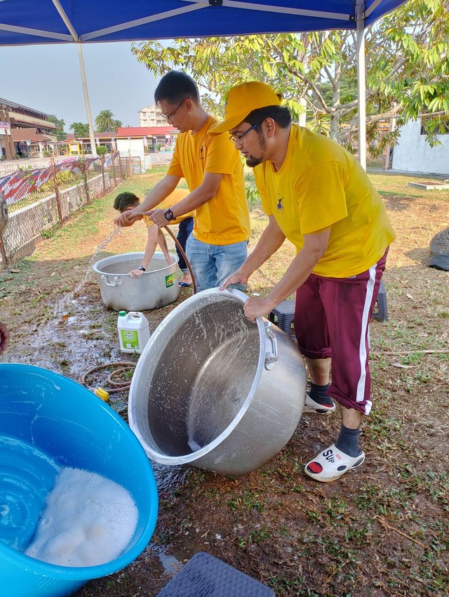 Aman Akil dan ahli pasukan membilas periuk besar di ruang mencuci peralatan kenduri.