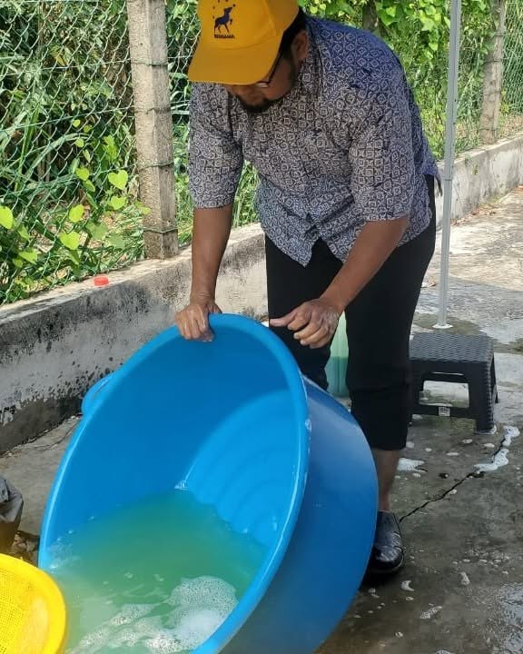 Air basuhan dituang daripada besen di kawasan mencuci pinggan.