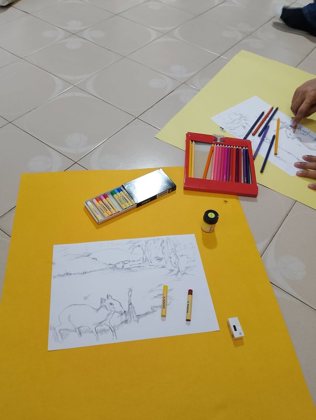 Kertas lukisan dan pensel warna disediakan di meja aktiviti mewarna.