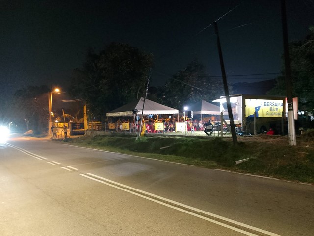 Pandangan lokasi ceramah pada waktu malam dengan pentas trak dan khemah hadirin di tepi jalan.