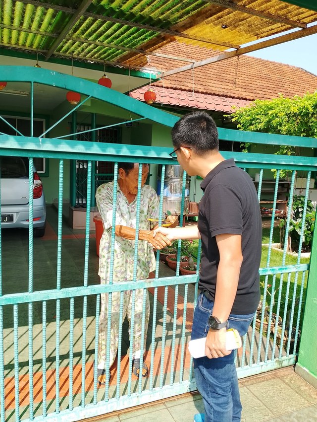 Seorang ahli pasukan bersalaman dengan penduduk ketika menyampaikan jemputan dari rumah ke rumah.