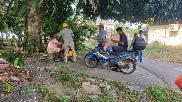 Pasukan menyapa warga setempat di tepi jalan berhampiran motosikal.