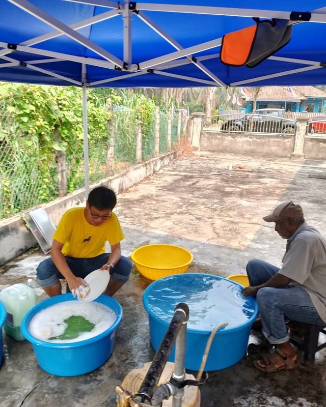 Petugas bekerjasama mencuci pinggan di bawah khemah.