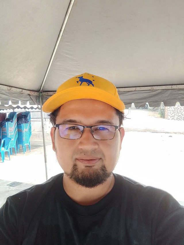 Aman Akil merakamkan foto di bawah khemah semasa persiapan kenduri.