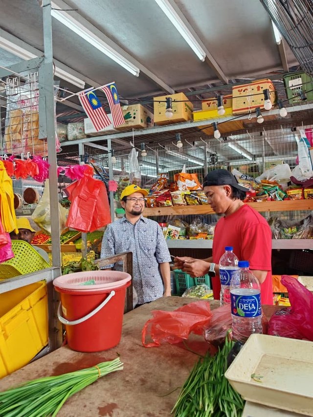 Aman Akil bersama seorang peniaga di gerai sayur dan barangan dapur.
