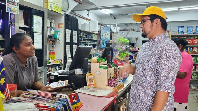 Aman Akil berbual dengan seorang peniaga di kaunter kedai.